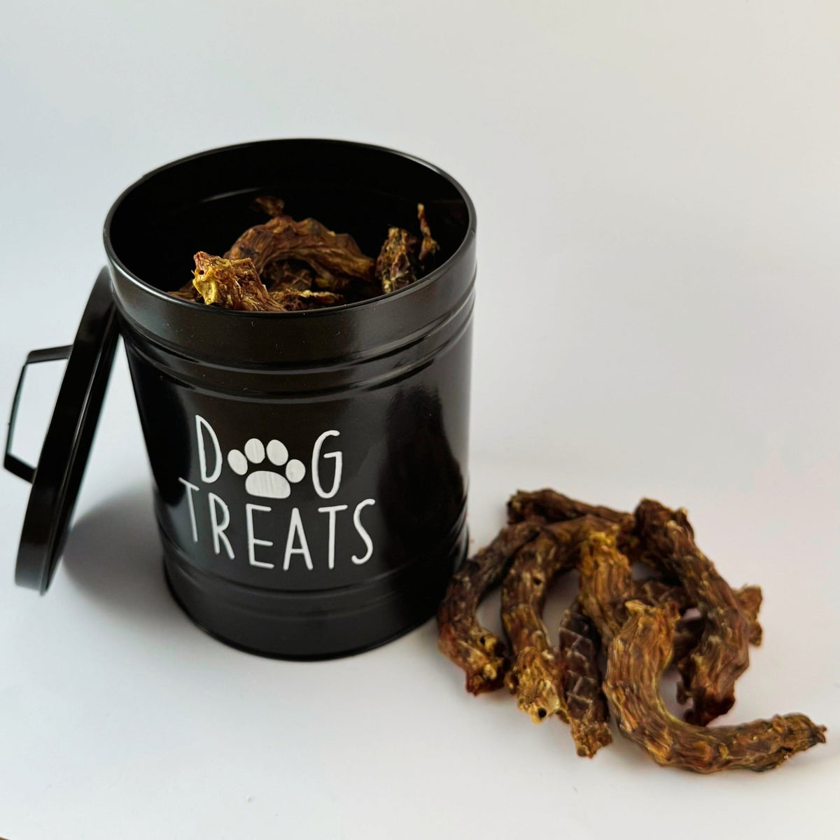 Dehydrated chicken necks in a black dog treat tin, with more necks beside it