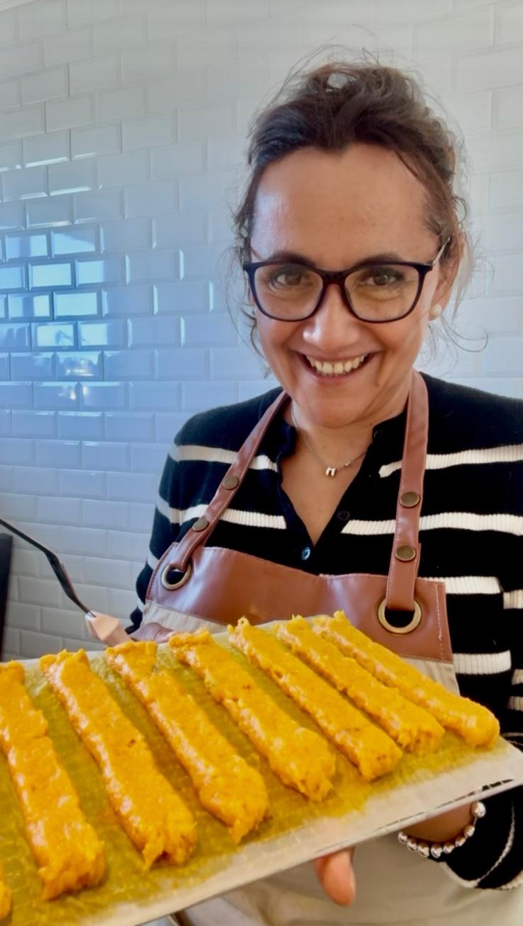 Massy smiling in her Sydney kitchen, holding a tray of hand-made Chicken Prime Sticks before drying